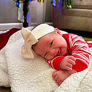 Caylin is registered to the contest to win money with this photo: baby, headband, bow, blanket, christmas_tree, christmas_lights, pajamas, red, white, smiling, indoor, floor, decorations, holiday, festive, cute, infant, toddler, happy, cozy