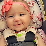 Aurora is registered to the contest to win money with this photo: baby, infant, smiling, headband, pink_bow, car_seat, safety_harness, floral_pattern, cute, closeup, child, face, portrait, happy, seatbelt, clothing, person, baby_girl, indoor, comfort