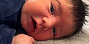 Lucas participe au concours pour gagner de l'argent avec cette photo : baby, blanket, blue_clothing, closeup, cute, expression, face, hand, indoors, infant, lying_down, newborn, person, portrait, resting, skin, sleepwear, soft, wooden_furniture, young_child