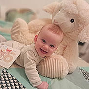 Tiago participe au concours pour gagner de l'argent avec cette photo : baby, smiling, stuffed_animal, sheep_toy, quilt, blanket, card, milestone, infant, cute, happy, crawling, indoors, child, face, portrait, soft_toy, clothing, head, toddler