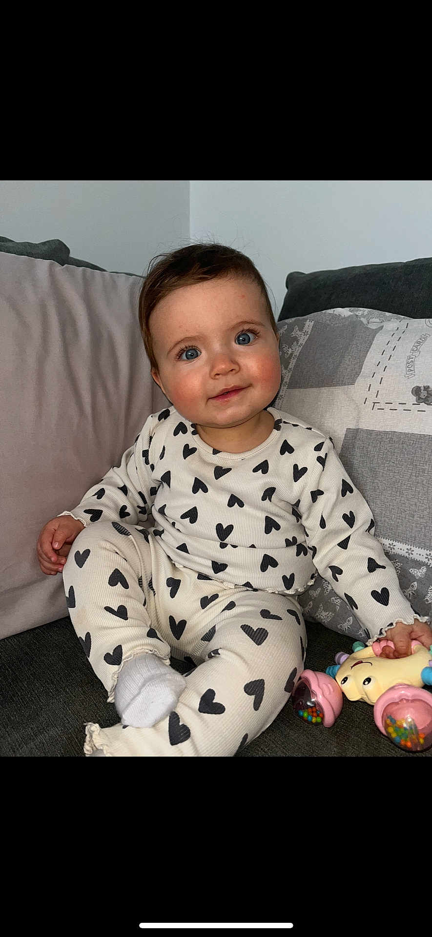 Thea is registered to the contest to win money with this photo: baby, child, heart_pattern, pajamas, toy, couch, pillow, indoor, smile, cute, infant, sitting, cozy, soft_lighting, portrait, happy, playful, young_child, comfortable, home