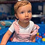 Thea is registered to the contest to win money with this photo: toddler, child, baby, blue_eyes, pink_clothing, white_bow, indoor, play_area, ball_pit, curious, cute, portrait, small_hands, short_hair, colorful, soft_lighting, focus, playful, young_child, person