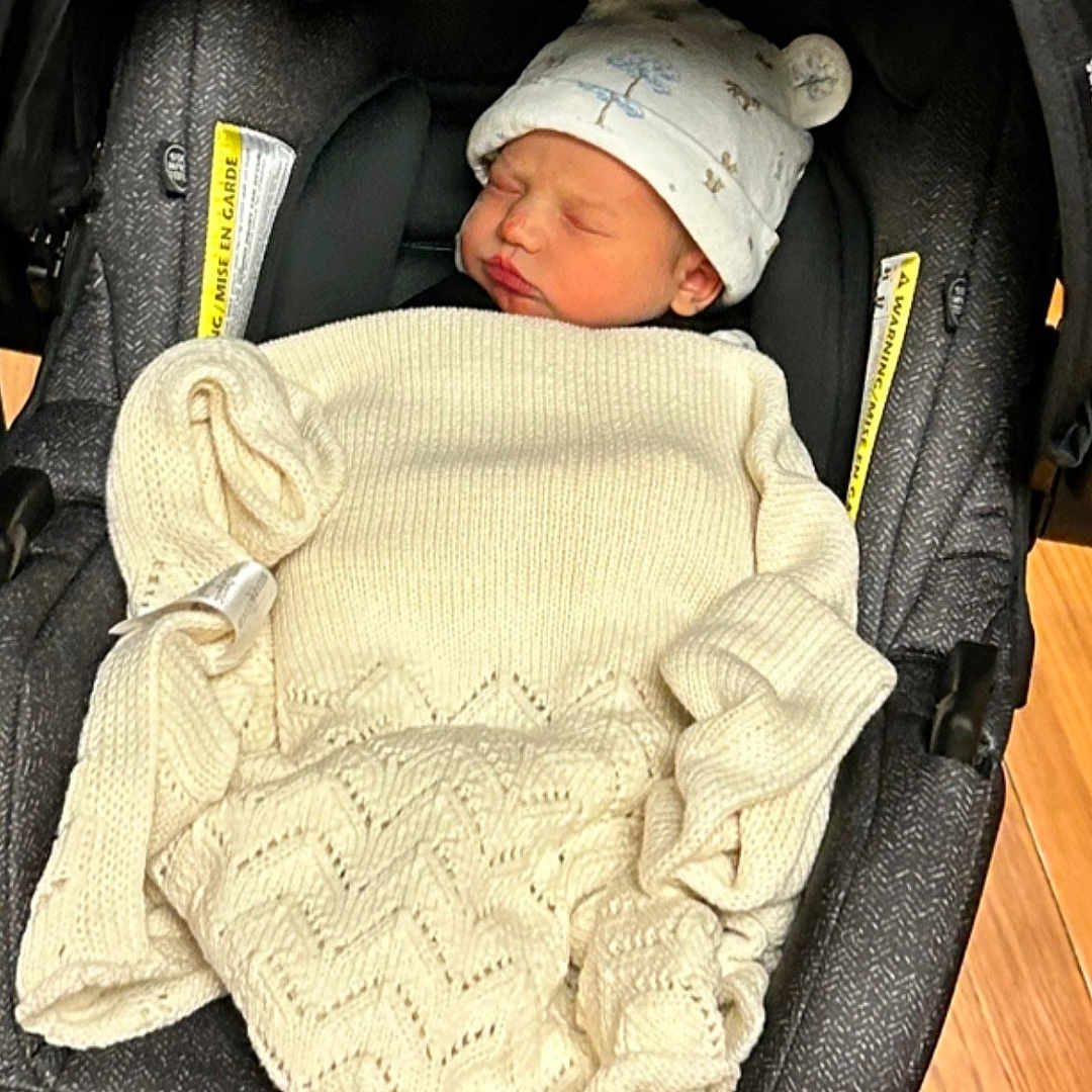 Brooks is registered to the contest to win money with this photo: baby, blanket, bonnet, car, clothing, coat, crib, face, furniture, hat, head, infantbed, jacket, newborn, person, photography, portrait, sleeping, transportation, vehicle