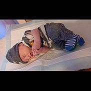 Bellamy is registered to the contest to win money with this photo: baby, blanket, child, clothing, comfort, cozy, cute, hat, indoor, infant, lying_down, newborn, nursery, peaceful, person, resting, sleeping, soft_surface, striped_socks, warm