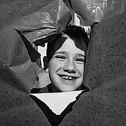 Gabriel participe au concours pour gagner de l'argent avec cette photo : child, boy, smile, face, portrait, wrapping_paper, tear, hole, black_and_white, holiday, penguin_pattern, snowflake_pattern, happy, closeup, playful, indoor, head, cute, young, cheerful