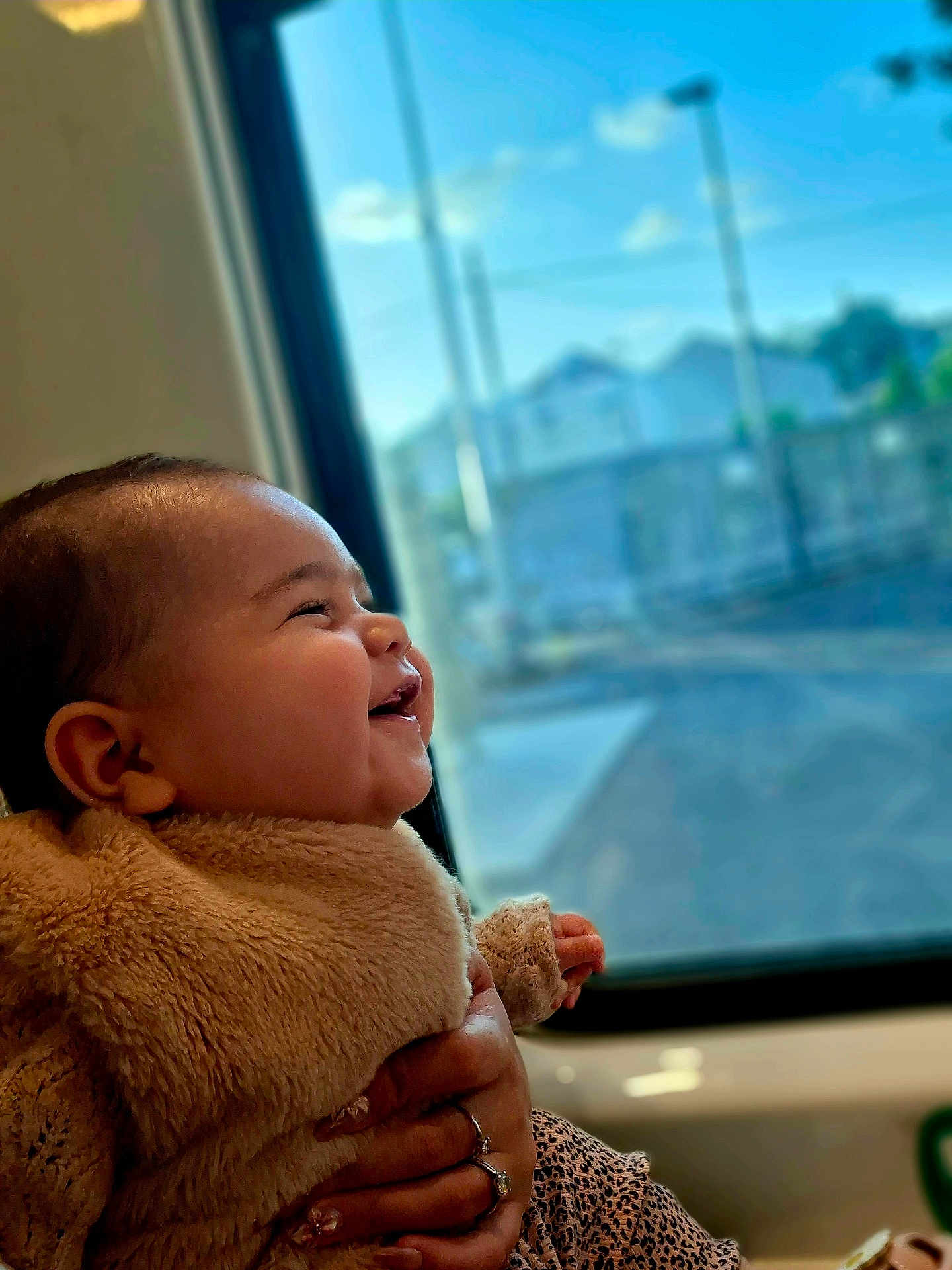 Ohana participe au concours pour gagner de l'argent avec cette photo : baby, smiling, child, fuzzy_clothing, hand, window, sunlight, indoor, portrait, happy, person, cozy, adult_hand, face, cute, warm, holding, infant, side_profile, daylight