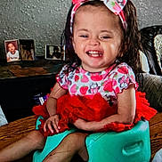 Denise joined the competition — help win amazing prizes! toddler, child, smiling, baby_seat, tutu, headband, living_room, table, photoframes, happy, clothing, person, furniture, indoor, cute, seat, colorful, hair, portrait, sitting