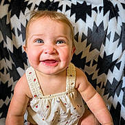 Delaney joined the competition — help win amazing prizes! baby, smiling, child, infant, cute, happy, sitting, blanket, pattern, clothing, face, portrait, indoors, skin, person, baby_girl, bright_eyes, cheerful, soft_texture, ladybug_print