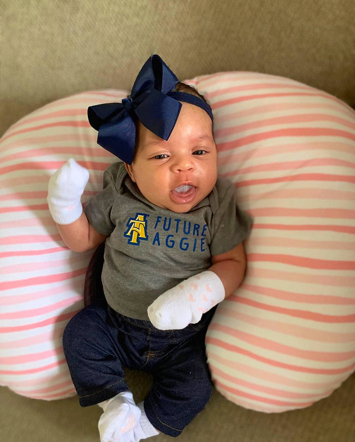 Alani is registered to the contest to win money with this photo: baby, baby_toddler_clothing, baseball_cap, cap, child, comfort, eye, finger, flooring, gesture, happy, head, headgear, person, personal_protective_equipment, sitting, skin, sleeve, textile, thumb