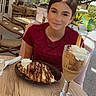 chair, chocolate, crepes, dessert, drink, face, food, girl, glass, iced_coffee, leafy, necklace, outdoor_cafe, person, red_shirt, smile, sunlight, table, tree, whipped_cream