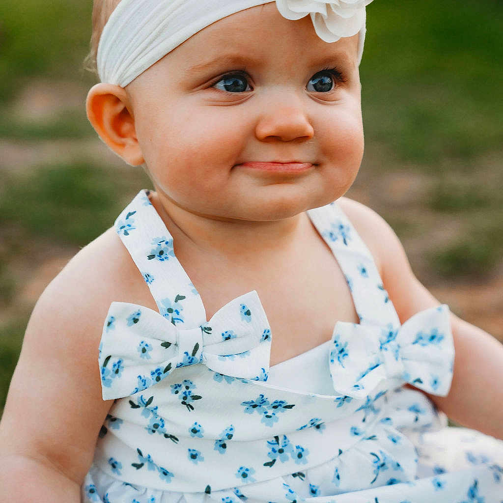 Tatum is registered to the contest to win money with this photo: baby, child, girl, headband, flower, dress, bow, blue_eyes, smile, outdoor, grass, portrait, cute, infant, summer, fashion, closeup, sitting, happy, person
