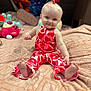 baby, child, smiling, sitting, blanket, plush_toy, bedroom, indoor, cute, happy, person, face, hair_tie, colorful, patterned_clothing, foot, playful, portrait, soft_texture, decor
