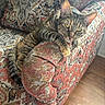 cat, tabby_cat, pet, animal, feline, striped_fur, green_eyes, whiskers, ears, paws, tail, lounging, relaxed, alert, portrait, armchair, upholstery, patterned_fabric, indoor, hardwood_floor