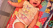 Mahi joined the competition — help win amazing prizes! arm, baby, blanket, child, clothing, colorful, cute, diaper, face, happy, indoor, infant, leg, lying_down, patchwork, person, playful, quilt, smile, toy