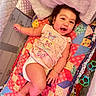 arm, baby, blanket, child, clothing, colorful, cute, diaper, face, happy, indoor, infant, leg, lying_down, patchwork, person, playful, quilt, smile, toy