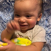 Levi is registered to the contest to win money with this photo: baby, smiling, blanket, colorful, happy, infant, child, cushion, furniture, indoors, cute, portrait, hand, face, skin, clothing, toddler, soft, texture, comfort