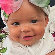 Anastasia is registered to the contest to win money with this photo: baby, child, smiling, face, headband, bow, flower, hand, person, portrait, cute, white_clothing, floral_pattern, infant, skin, eyes, happy, closeup, outdoor, baby_girl