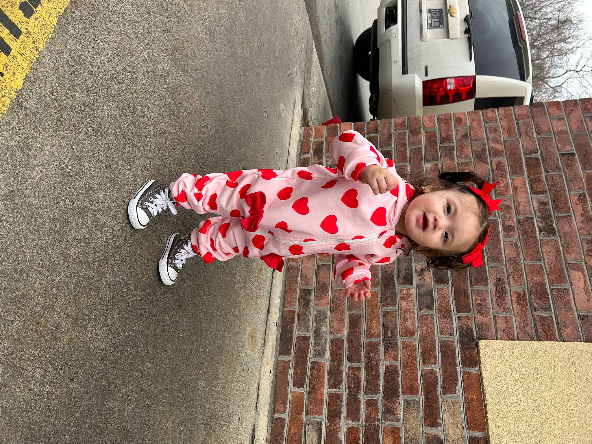 Jianna is registered to the contest to win money with this photo: asphalt, automotive_design, automotive_exterior, automotive_lighting, automotive_tire, car, carmine, floor, flooring, human_leg, motor_vehicle, pattern, person, red, road, road_surface, sidewalk, toddler, toy, tree
