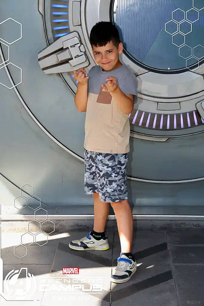 avengers, background, boy, branding, child, floor, graphic, hexagons, marvel, metallic, outdoor, playful, pose, shadow, shorts, smile, sneakers, standing, superhero, tshirt