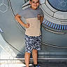 avengers, background, boy, campus, child, floor, hands_on_hips, hexagons, light, logo, marvel, outdoor, posing, science_fiction, shadow, shorts, smiling, sneakers, standing, tshirt