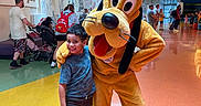 Mikael joined the competition — help win amazing prizes! backpack, boy, cartoon_art, ceiling, child, costume, family, floor, happy, indoor, lighting, mascot, people, pluto, shoes, shorts, smile, stroller, tshirt, wall_art