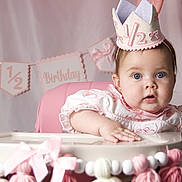 Autumn is registered to the contest to win money with this photo: baby, child, party_hat, high_chair, birthday, half_birthday, pink, pastel, decoration, ribbon, tassel, face, cute, celebration, infant, clothing, expression, indoor, person, portrait