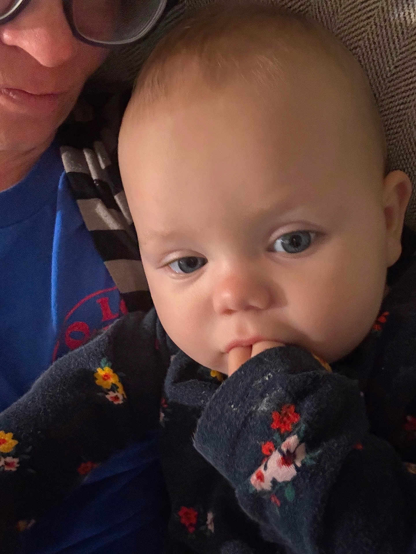 Gemia is registered to the contest to win money with this photo: baby, child, face, blue_eyes, hand, sweater, floral_pattern, adult, glasses, close_up, portrait, indoor, person, candid, soft_light, skin, expression, comfort, clothing, human
