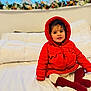 toddler, child, red_jacket, hood, boots, white_bed, flower_arrangement, window, indoors, cute, smiling, sitting, warm_clothing, face, person, home, soft_lighting, cozy, curious, young_child