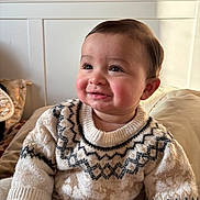 Yanis a rejoint le concours — aidez-le/la à gagner de superbes lots ! baby, child, smiling, sweater, indoor, cozy, patterned_clothing, face, cheeks, person, cute, warm_light, seated, portrait, infant, soft_texture, head, happy, young, rosy_cheeks