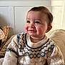 baby, child, smiling, sweater, indoor, cozy, patterned_clothing, face, cheeks, person, cute, warm_light, seated, portrait, infant, soft_texture, head, happy, young, rosy_cheeks