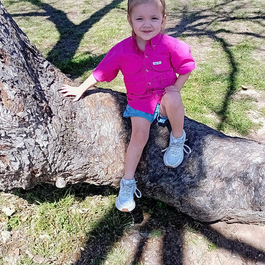 Ella joined the competition — help win amazing prizes! clothing, face, footwear, grass, grove, head, land, nature, outdoors, park, person, photography, plant, portrait, rock, shoe, shorts, tree, vegetation, woodland