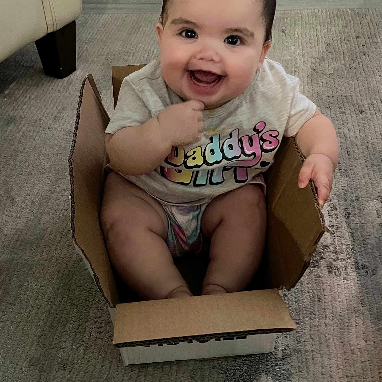 Ari joined the competition — help win amazing prizes! baby, box, city, clothing, face, happy, head, laughing, pants, person, photography, plant, portrait, pottedplant, road, sitting, smile, street, t_shirt, urban