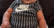 Winta is registered to the contest to win money with this photo: baby, bed, bow, child, chubby_cheeks, cute, hand, happy, headband, indoor, infant, legs, onesie, person, pillow, sitting, skin, smiling, soft_lighting, striped_clothing