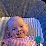 Faith is registered to the contest to win money with this photo: baby, smile, infant, pink_clothing, pacifier, cushion, seat, face, head, arm, happy, indoors, child, person, cute, skin, young, comfort, portrait, closeup