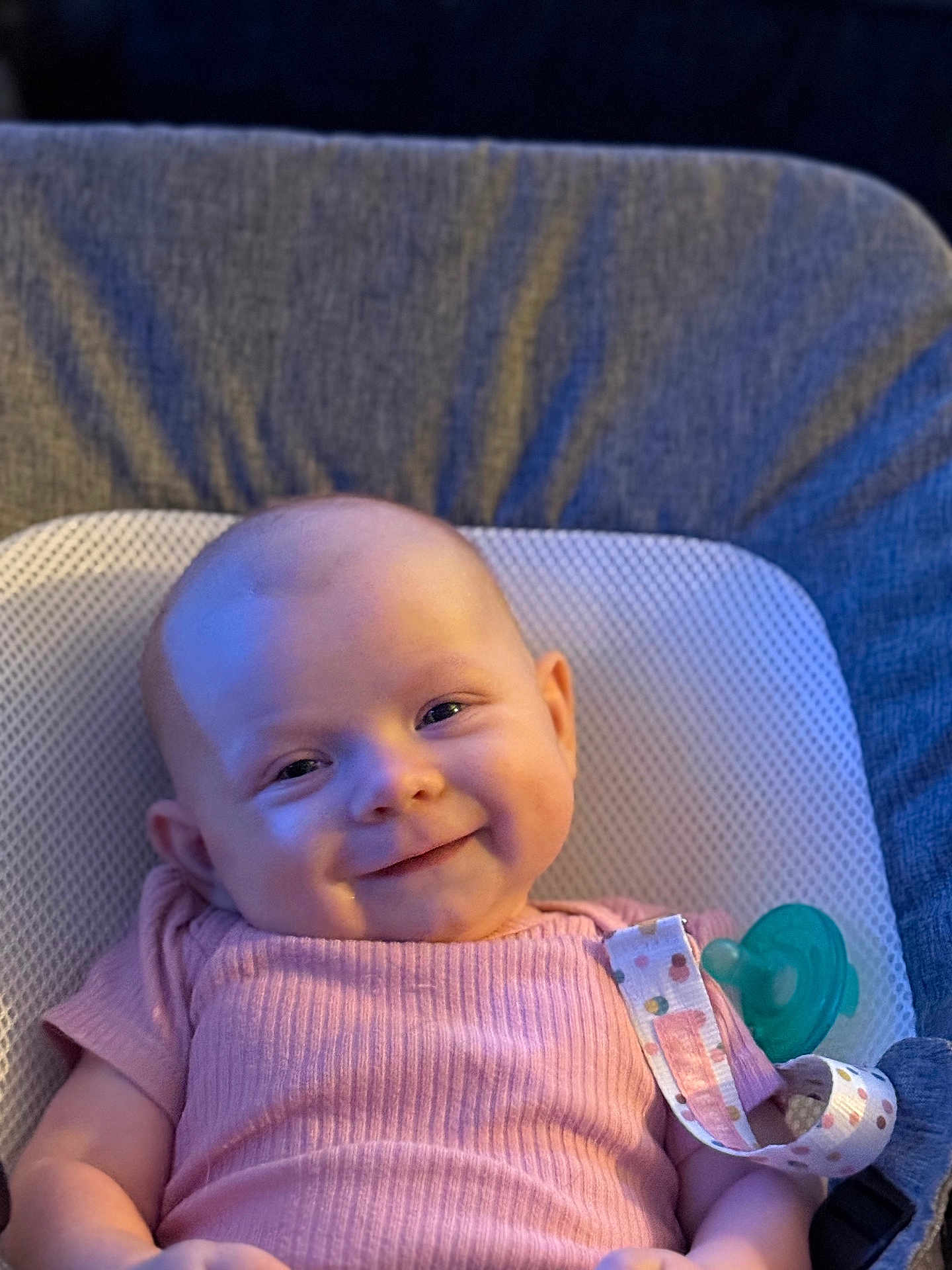 Faith is registered to the contest to win money with this photo: baby, smile, infant, pink_clothing, pacifier, cushion, seat, face, head, arm, happy, indoors, child, person, cute, skin, young, comfort, portrait, closeup