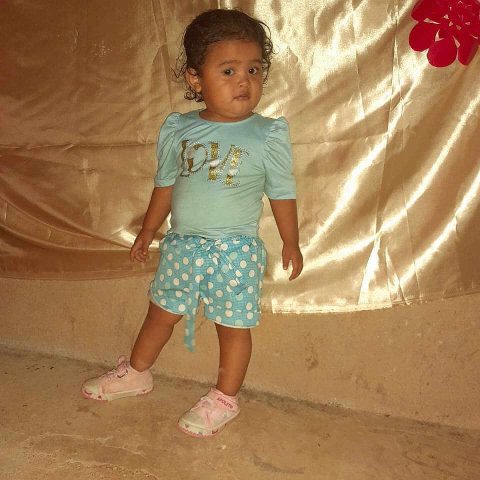 Karleyvis joined the competition — help win amazing prizes! blue_shirt, butterfly, casual_clothing, child, concrete_floor, curly_hair, cute, decorations, expression, flower, gold_backdrop, heart_shape, indoor, person, pink_shoes, polka_dot_shorts, portrait, small_child, standing, toddler