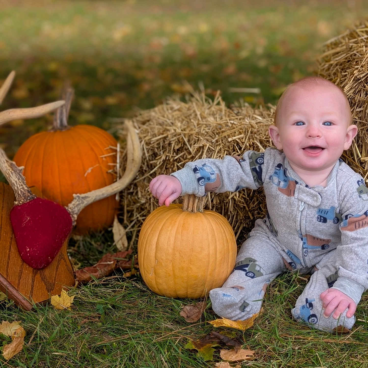 Thad is registered to the contest to win money with this photo: antler_mount, autumn, baby, blue_eyes, child, cute, decor, fall, grass, hay_bale, leaves, nature, outdoor, pajamas, person, pumpkin, rustic, seasonal, sitting, smiling