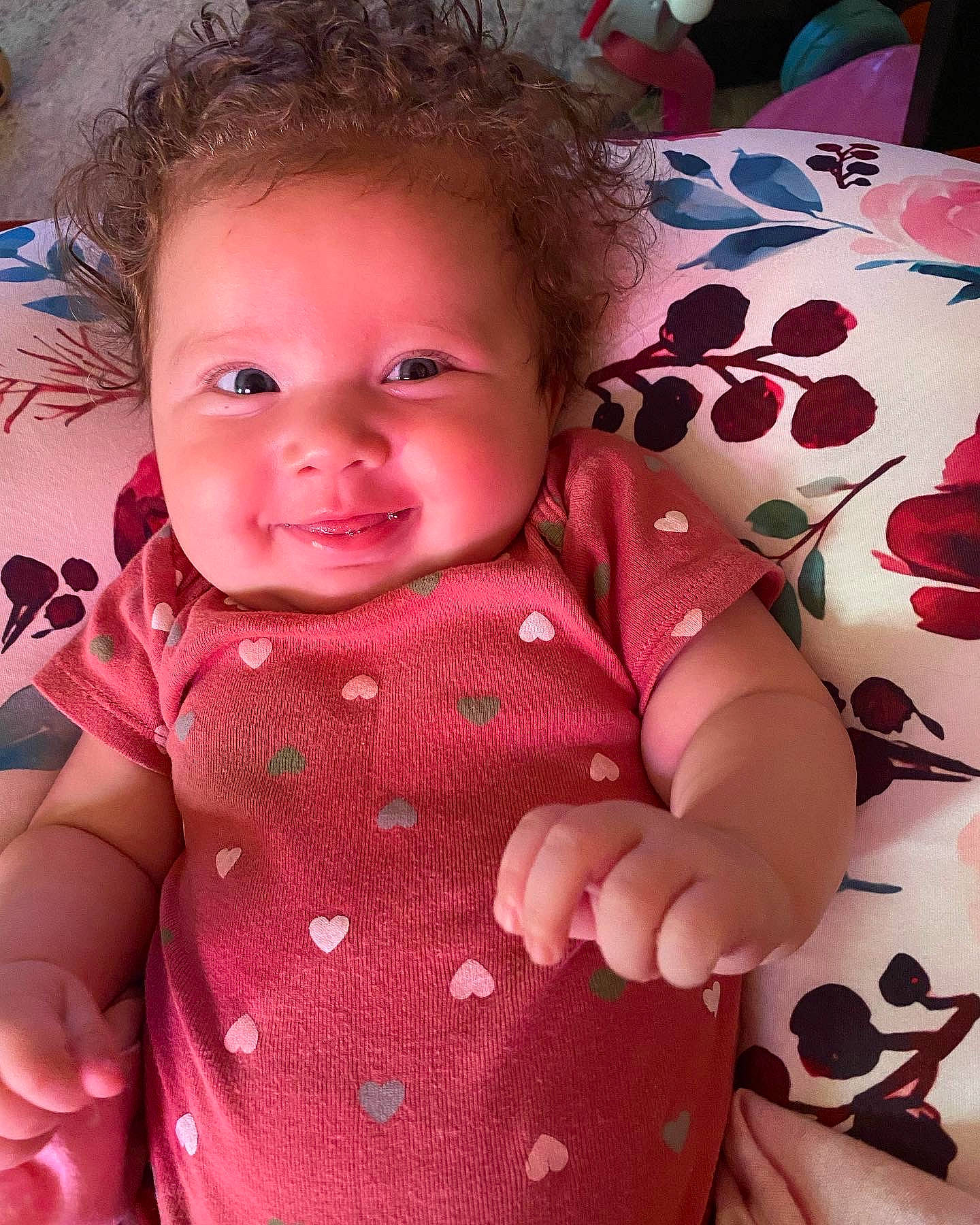 Jocelynn is registered to the contest to win money with this photo: baby, baby_toddler_clothing, cheek, eye, facial_expression, finger, gesture, hand, happy, head, human_body, linens, lip, nose, pattern, people, person, pink, skin, sleeve