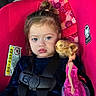 toddler, child, car_seat, doll, pink, blonde_hair, serious_expression, seatbelt, patterned_fabric, indoors, person, clothing, toy, portrait, young_child, face, hair_tied, sitting, seat, warning_label