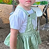child, toddler, girl, outdoor, green_dress, white_shirt, boots, bracelet, hair_bows, blue_eyes, standing, dirt_ground, party, table, chair, expression, cute, casual_clothing, daylight, portrait