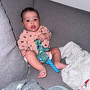 Léo participe au concours pour gagner de l'argent avec cette photo : baby, blanket, cloth, couch, cozy, cushion, drool, eyes, face, hands, indoor, infant, legs, onesie, plush_toy, portrait, sitting, sofa, toes, wall