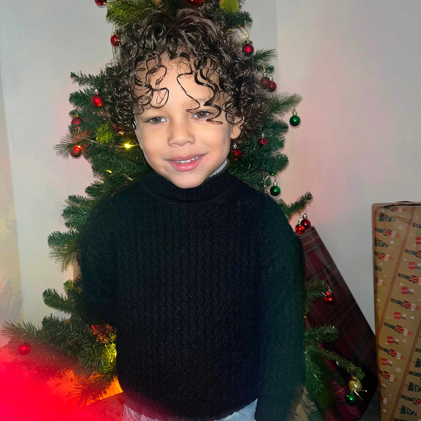 Karnelo joined the competition — help win amazing prizes! black_sweater, blue_jeans, casual_pose, celebration, child, christmas_lights, christmas_ornaments, christmas_tree, curly_hair, festive, gift_wrap, happy, holiday, holiday_decor, indoor, portrait, present, seasonal, smiling, young_child