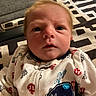 Carson is registered to the contest to win money with this photo: baby, infant, face, eyes, onesie, clothing, whale_patch, anchors, patterned_background, indoor, person, cute, portrait, newborn, young_child, expression, closeup, head, soft_lighting, fabric