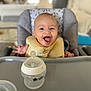 Aylan participe au concours pour gagner de l'argent avec cette photo : baby, bib, bottle, child, clothing, cute, expression, face, feeding, furniture, happy, high_chair, indoor, infant, mouth_open, person, plastic, smiling, table, young