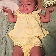 Isabella is registered to the contest to win money with this photo: baby, infant, yellow_outfit, blanket, lying_down, baby_wipes, soft_texture, curious_expression, arms_outstretched, indoors, child, clothing, skin, head, legs, feet, face, person, toddler, smile