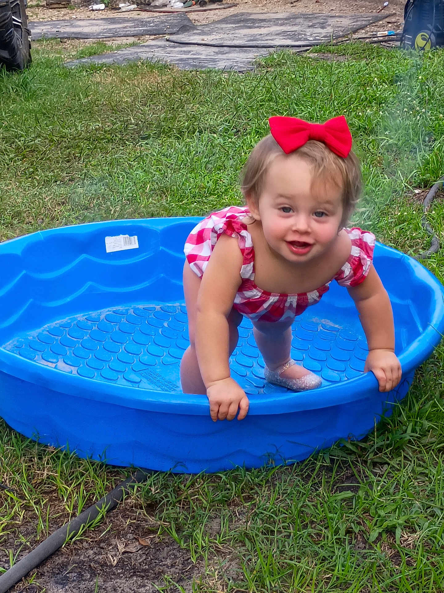 Cheyenne joined the competition — help win amazing prizes! toddler, child, red_bow, blue_pool, grass, outdoor, play, happy, smile, shoes, plastic_pool, checkered_clothing, baby, person, summer, yard, fun, cute, nature, daylight