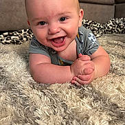 Easton is registered to the contest to win money with this photo: baby, smiling, happy, infant, rug, carpet, living_room, couch, child, cute, skin, hands, clothing, indoors, portrait, human, baby_clothes, closeup, playful, young_child