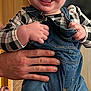 Easton joined the competition — help win amazing prizes! baby, child, smile, happy, denim_overalls, checkered_shirt, indoor, person, cute, holding_hands, portrait, young_child, face, eyes, hands, clothing, background, home, skin, expression