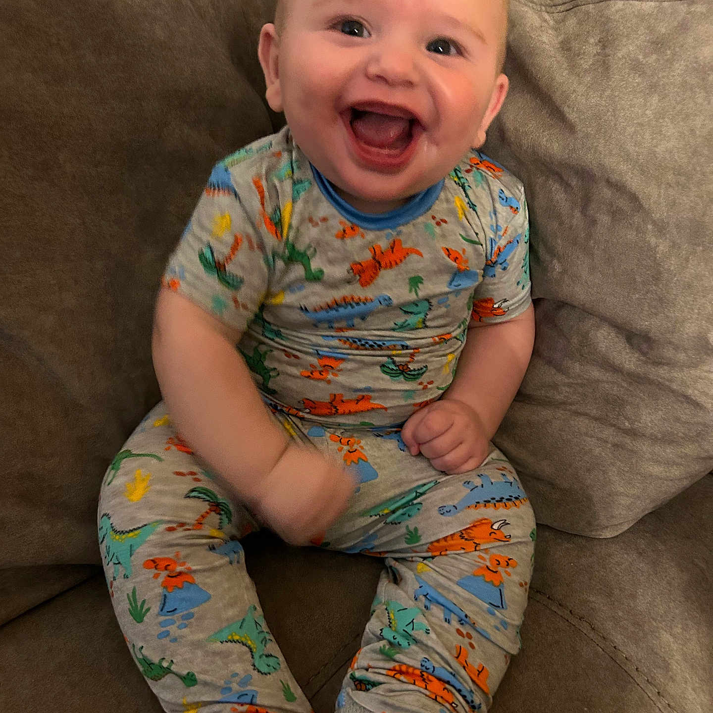 Easton joined the competition — help win amazing prizes! baby, child, clothing, comfortable, couch, cozy, cute, dinosaur_print, happy, indoor, infant, laughing, living_room, pajamas, person, playful, portrait, sitting, smiling, young