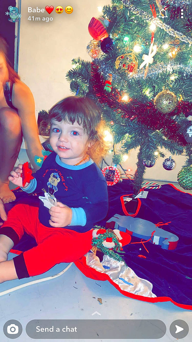 Zander is registered to the contest to win money with this photo: child, christmas, christmas_decoration, christmas_eve, christmas_ornament, christmas_tree, event, fictional_character, fun, happy, holiday, interior_design, person, plant, play, red, smile, toddler, tree